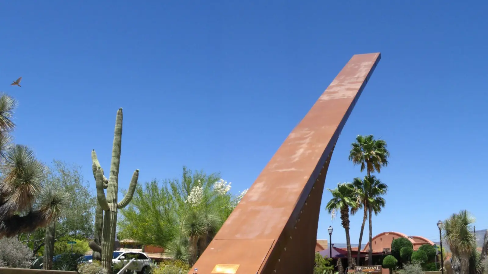 The Carefree Sundial against a blue sky, with saguaros and palms, in Carefree, Arizona