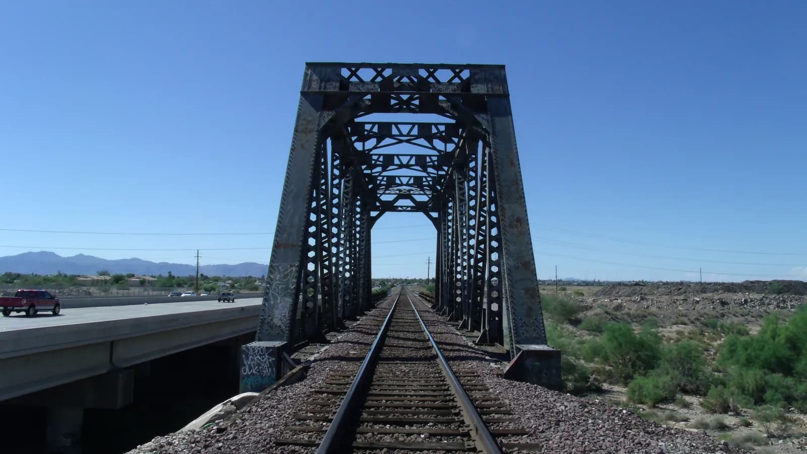 Historic 1895 railroad truss bridge over the Agua Fria River at El Mirage, Arizona, under a clear blue sky