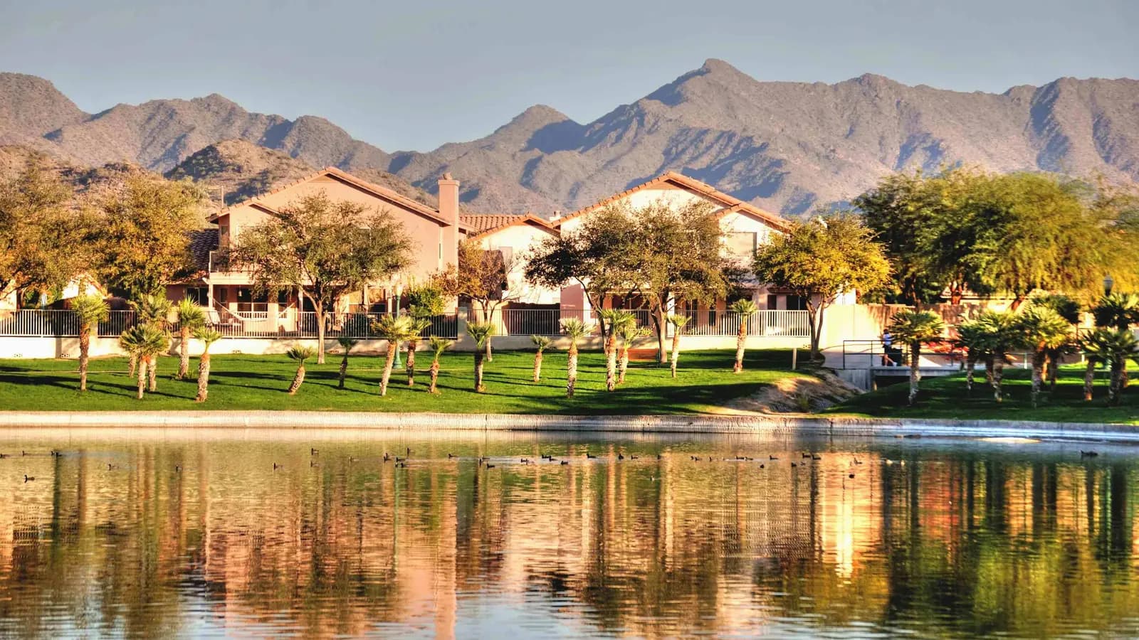 Lakefront homes in Goodyear's Estrella community reflected in a lake beneath the Sierra Estrella peaks