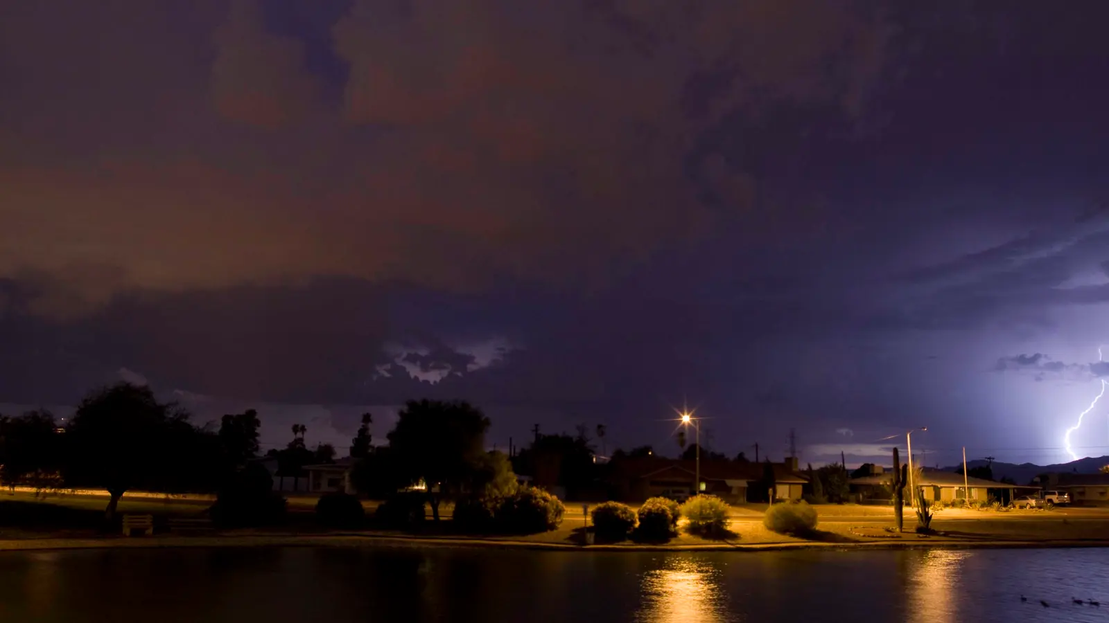 Monsoon lightning over Maricopa Lake and lakeside homes in Youngtown, Arizona, at night
